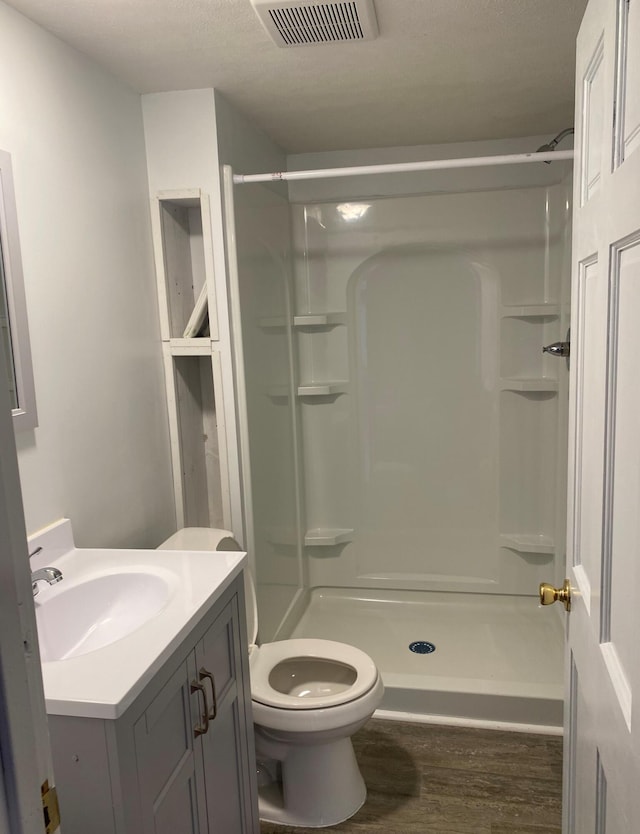 bathroom with walk in shower, vanity, a textured ceiling, hardwood / wood-style floors, and toilet