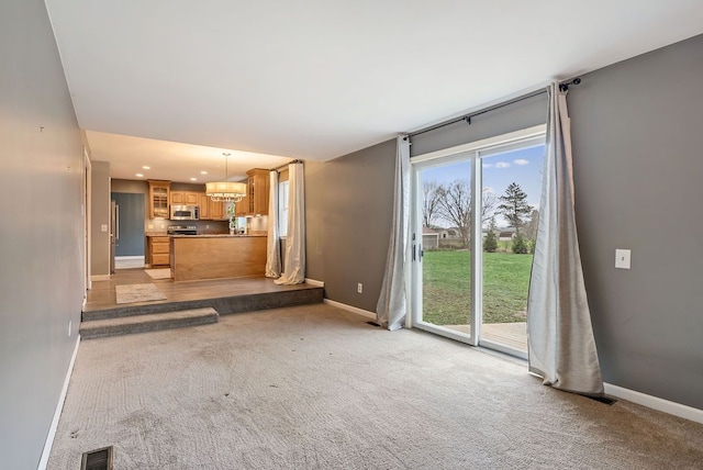 unfurnished living room with a chandelier and light colored carpet