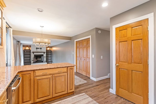 kitchen featuring pendant lighting, light hardwood / wood-style floors, light stone counters, and a chandelier