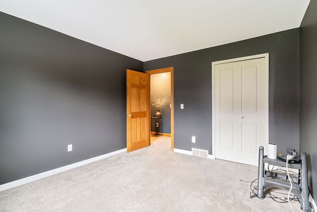 unfurnished bedroom with light colored carpet and a closet