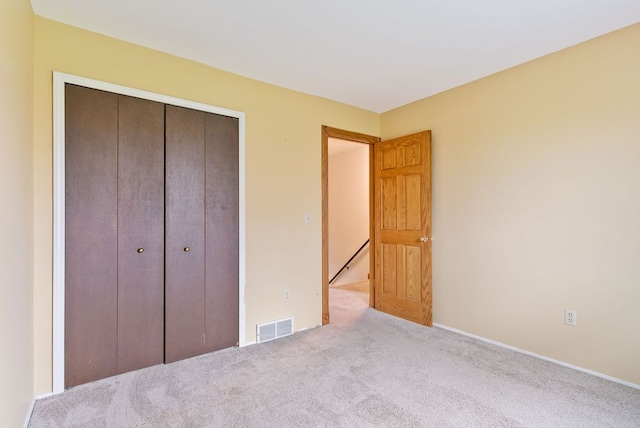 unfurnished bedroom with light carpet and a closet