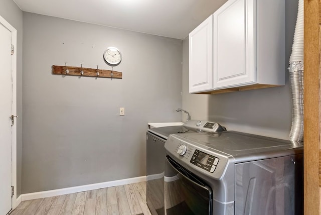 washroom with washer and dryer, cabinets, and light wood-type flooring