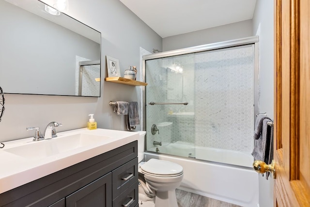 full bathroom featuring hardwood / wood-style floors, vanity, enclosed tub / shower combo, and toilet