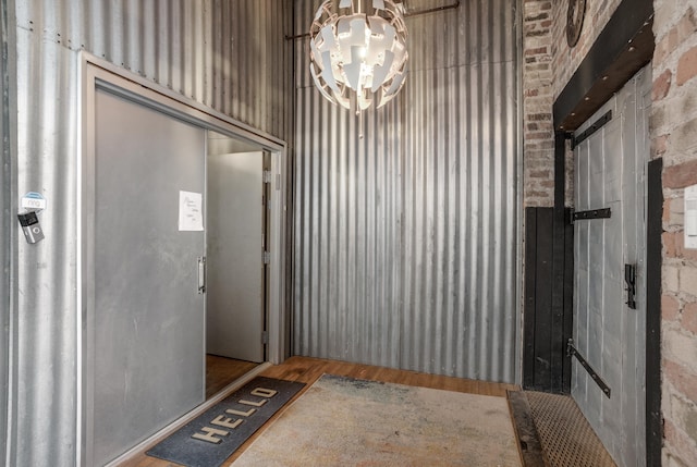 foyer entrance featuring a chandelier, hardwood / wood-style flooring, and brick wall