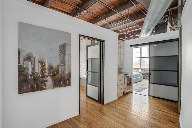 corridor with beamed ceiling, light hardwood / wood-style floors, and wooden ceiling