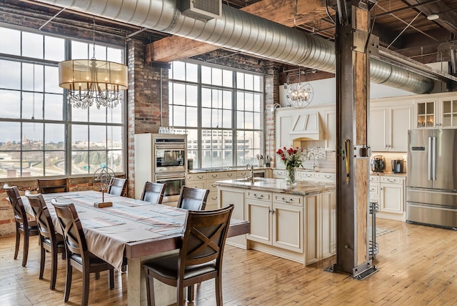 dining area featuring a notable chandelier, plenty of natural light, light wood-type flooring, and sink