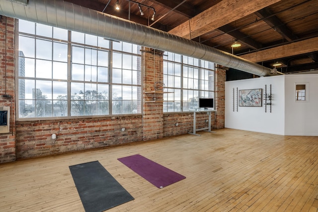 interior space featuring a healthy amount of sunlight, light wood-type flooring, and brick wall