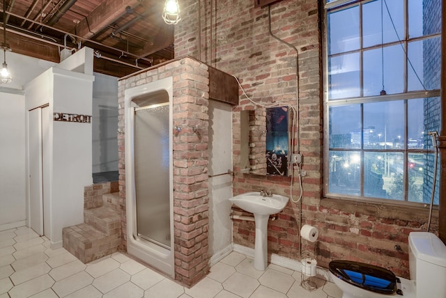 bathroom featuring sink, toilet, an enclosed shower, and brick wall