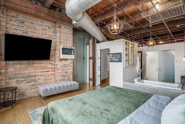 bedroom featuring hardwood / wood-style flooring, heating unit, and brick wall