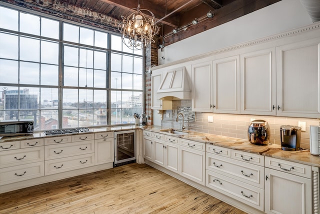 kitchen with white cabinetry, sink, beverage cooler, and light hardwood / wood-style floors