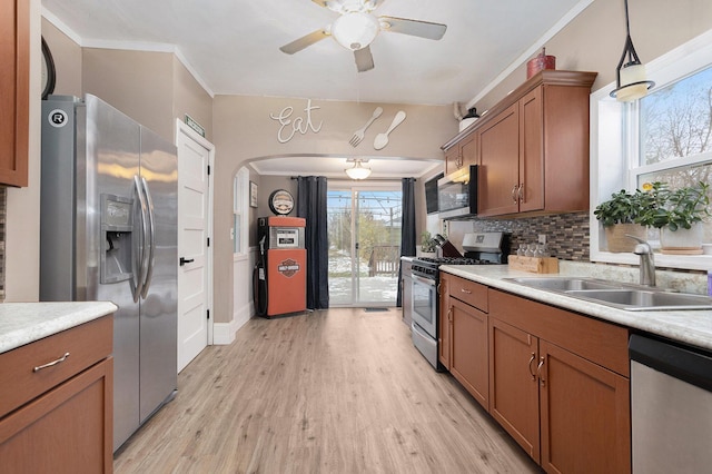 kitchen with stainless steel appliances, ceiling fan, sink, decorative light fixtures, and light hardwood / wood-style floors