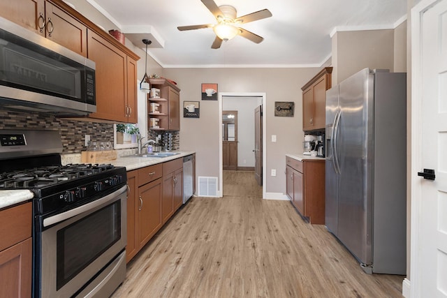 kitchen with sink, hanging light fixtures, light wood-type flooring, tasteful backsplash, and stainless steel appliances