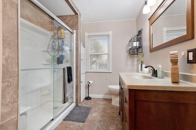 bathroom with vanity, toilet, a shower with door, and crown molding