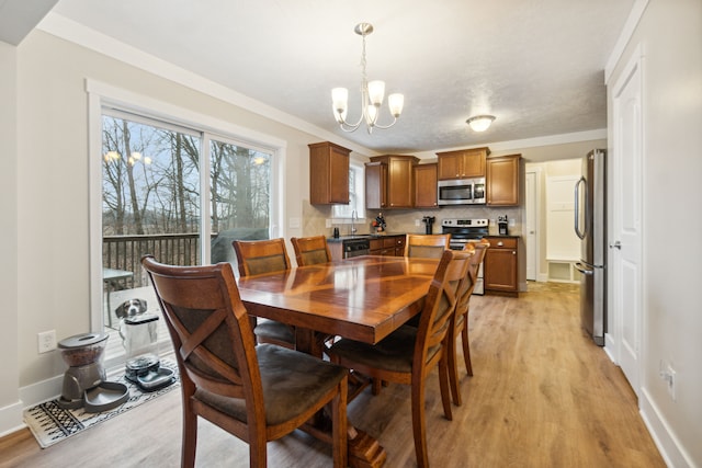 dining room featuring a chandelier, crown molding, sink, and light hardwood / wood-style flooring