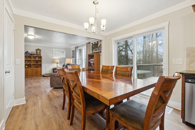 dining room with a notable chandelier, plenty of natural light, ornamental molding, and light hardwood / wood-style flooring