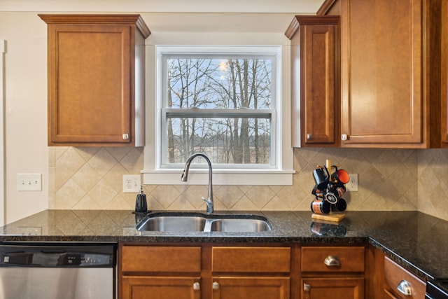 kitchen featuring dark stone countertops, sink, stainless steel dishwasher, and plenty of natural light