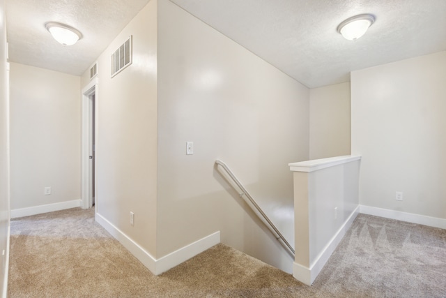 hall featuring a textured ceiling and light carpet