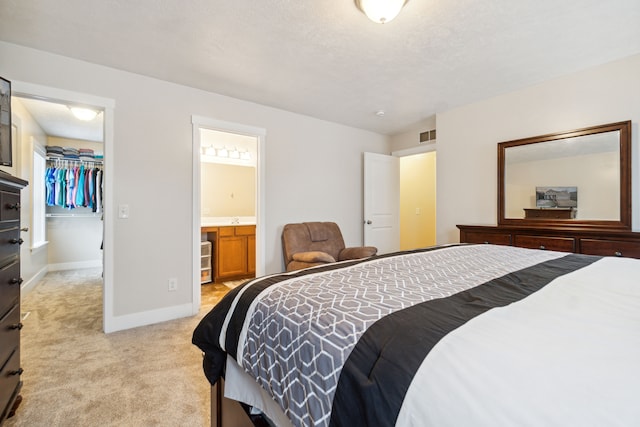 carpeted bedroom featuring a textured ceiling, ensuite bath, a spacious closet, and a closet