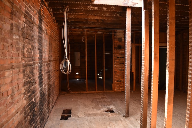 miscellaneous room with electric panel and brick wall