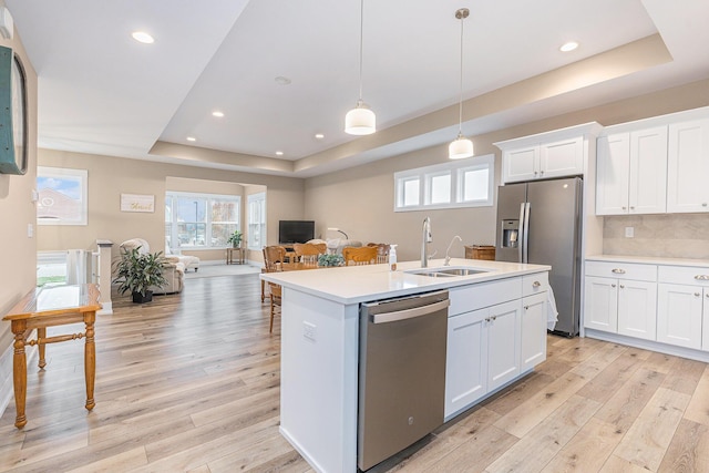 kitchen featuring decorative light fixtures, white cabinetry, a raised ceiling, and stainless steel appliances