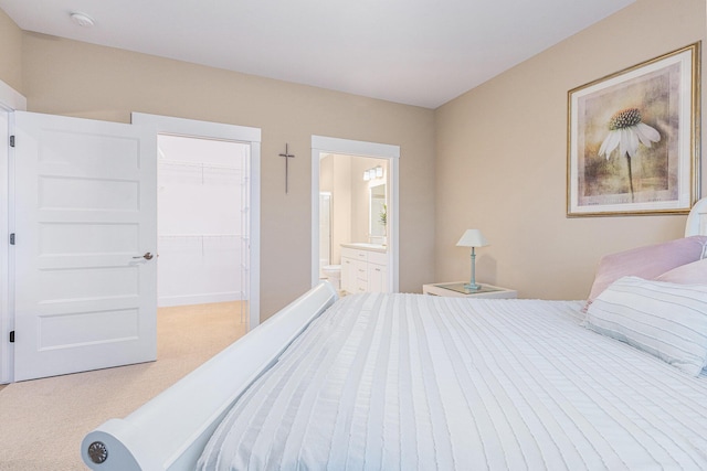 carpeted bedroom featuring ensuite bathroom, a closet, and a walk in closet