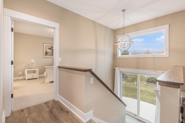 stairs featuring wood-type flooring, plenty of natural light, and a notable chandelier