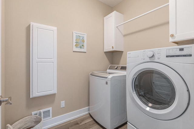 laundry area featuring cabinets, washer and clothes dryer, and light wood-type flooring