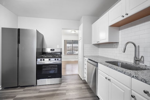 kitchen with white cabinetry, sink, light stone counters, and appliances with stainless steel finishes