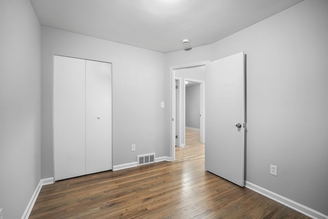 unfurnished bedroom featuring dark hardwood / wood-style floors and a closet