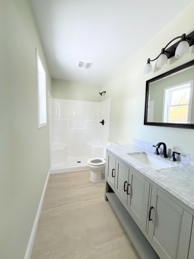 bathroom featuring visible vents, baseboards, toilet, vanity, and a shower