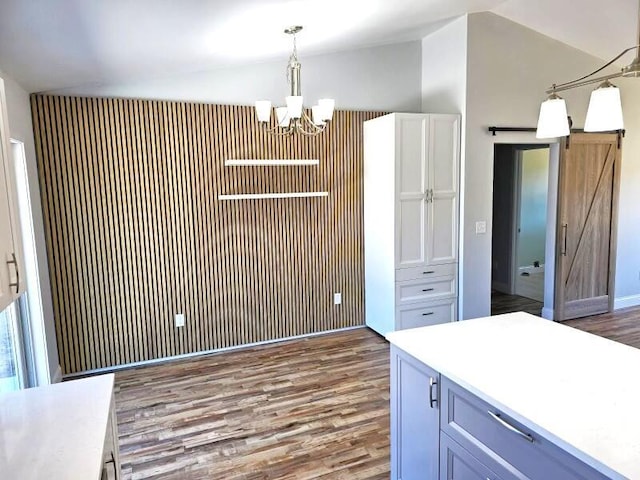 kitchen with wood finished floors, lofted ceiling, a barn door, decorative light fixtures, and a notable chandelier