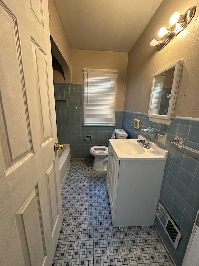 bathroom with vanity, toilet, and tile walls