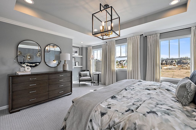 carpeted bedroom featuring a tray ceiling and an inviting chandelier