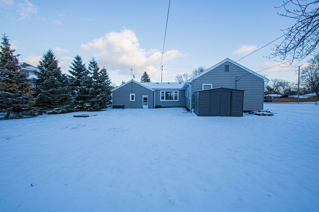 snow covered house featuring a storage unit