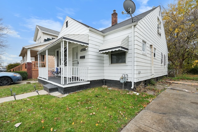 view of side of property with covered porch and a yard