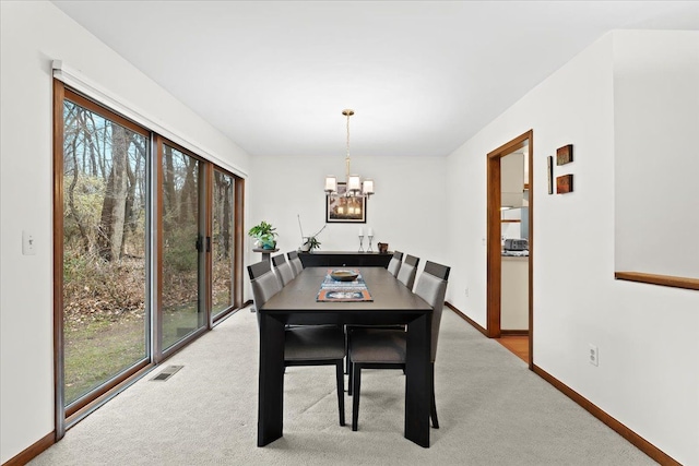 carpeted dining room with a wealth of natural light and a chandelier