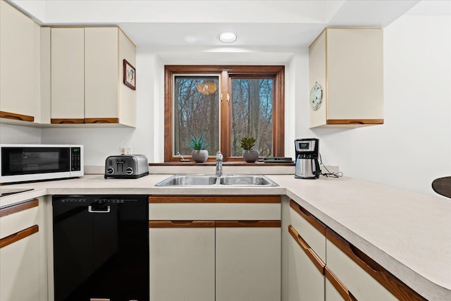 kitchen featuring cream cabinets, black dishwasher, and sink