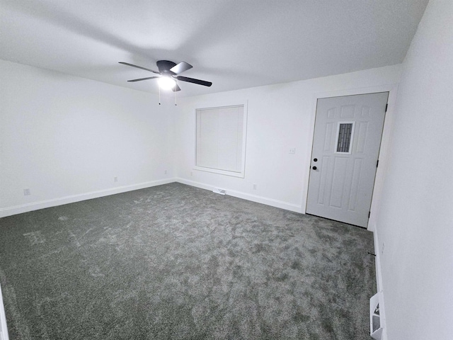 spare room with dark colored carpet and ceiling fan