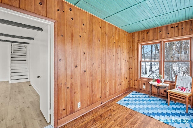 living area featuring light wood-type flooring, wooden ceiling, and wooden walls