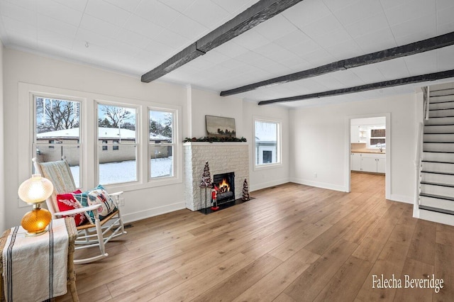 sitting room with beam ceiling, sink, light wood-type flooring, and a fireplace