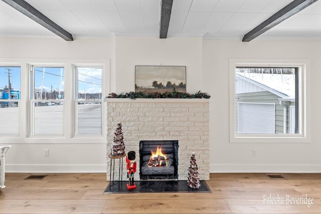 living room featuring beam ceiling, a fireplace, and light hardwood / wood-style flooring