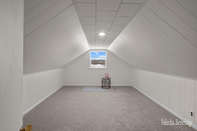 bonus room with carpet floors, wooden walls, and lofted ceiling