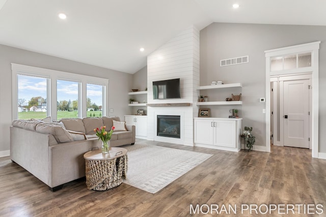 living room featuring hardwood / wood-style flooring, a fireplace, and high vaulted ceiling