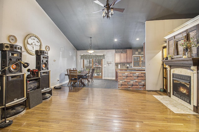 living room with ceiling fan, hardwood / wood-style floors, and vaulted ceiling