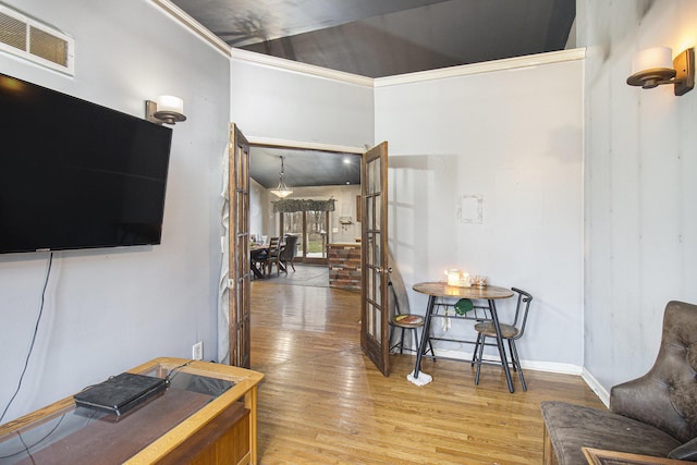 living room with wood-type flooring, crown molding, and french doors