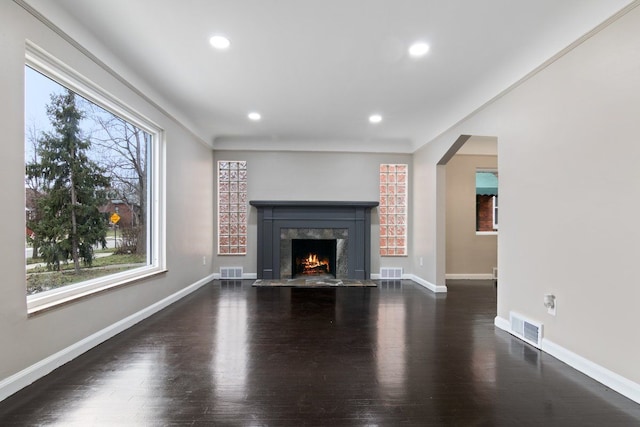 unfurnished living room featuring crown molding, dark wood-type flooring, and a high end fireplace