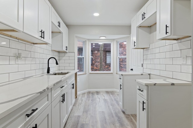 kitchen with white cabinetry, sink, and light wood-type flooring