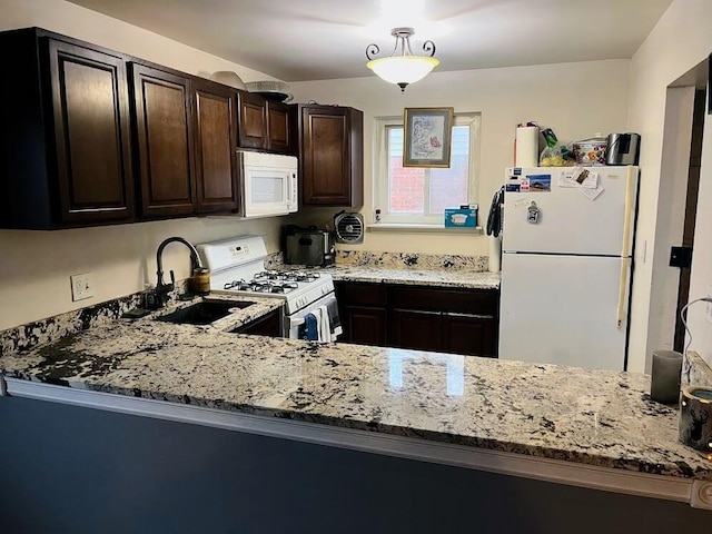 kitchen with light stone counters, dark brown cabinets, white appliances, and sink