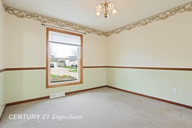 carpeted empty room featuring a chandelier