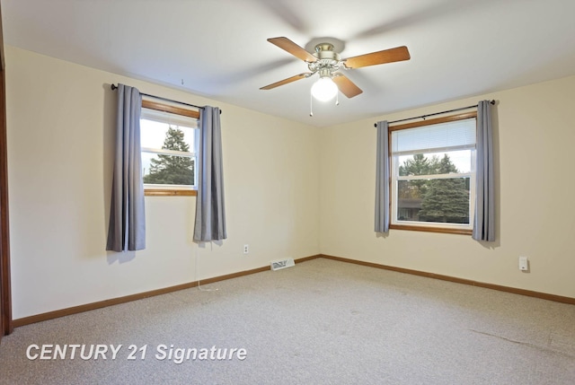 carpeted spare room featuring a wealth of natural light and ceiling fan